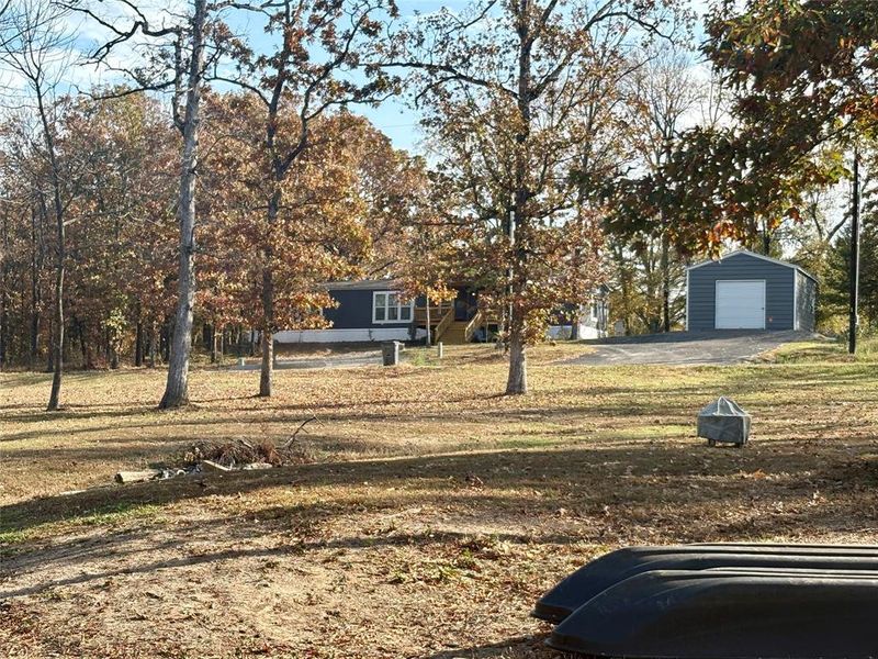 View of green lawn featuring an outbuilding, asphalt driveway, and a detached garage