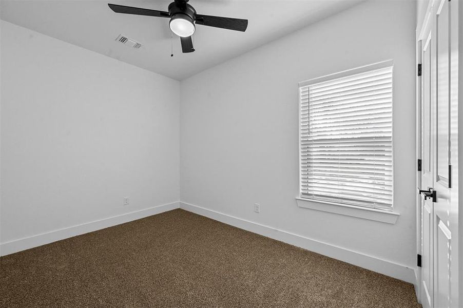 Empty room featuring ceiling fan, carpet floors, and a healthy amount of sunlight