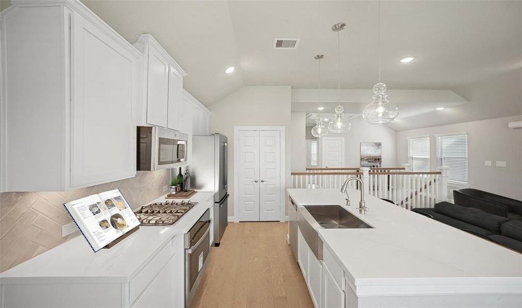 The chic white cabinetry offers plenty of storage space. The kitchen also features a gas range, and pantry.