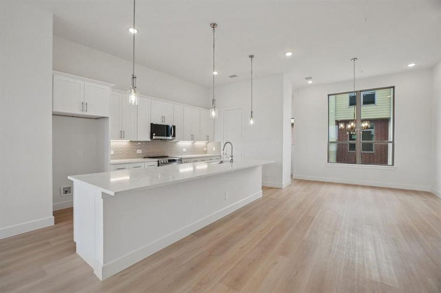 Kitchen with white cabinetry, a large island, pendant lighting, decorative backsplash, and recessed lighting