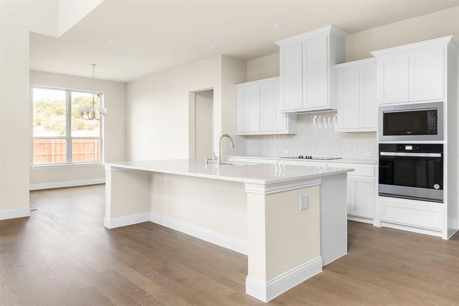 Kitchen featuring light hardwood / wood-style flooring, backsplash, black appliances, hanging light fixtures, and sink