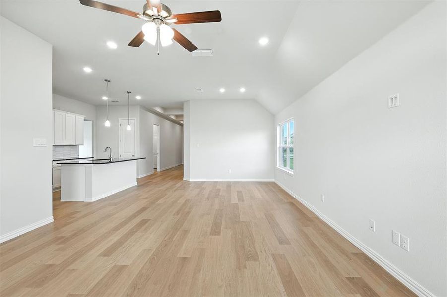 Unfurnished living room featuring recessed lighting, ceiling fan, light wood-type flooring, and lofted ceiling Unfurnished living room featuring recessed lighting, ceiling fan, light wood-type flooring, and lofted ceiling