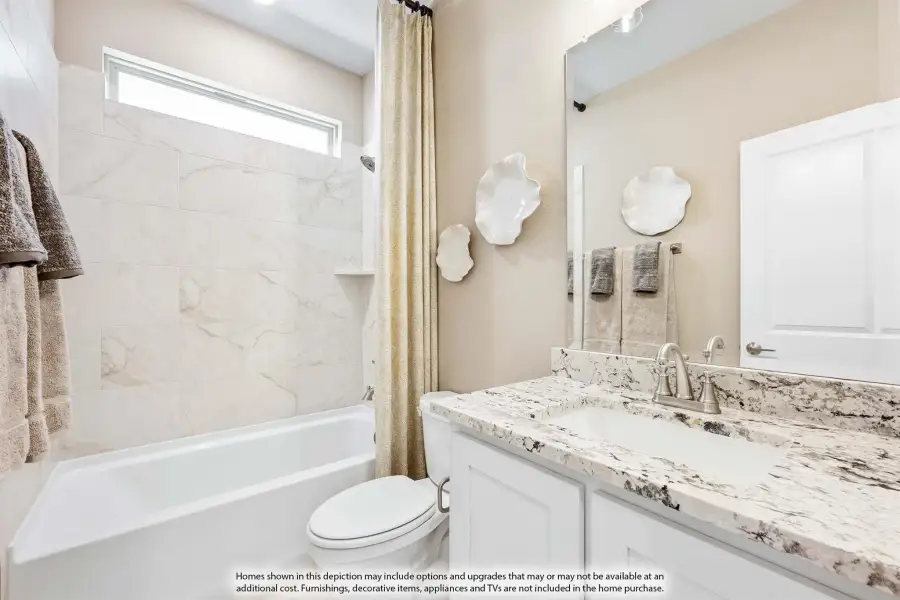 Bathroom with white cabinets, granite countertop, tub-shower combo with marble tile surround, and large mirror