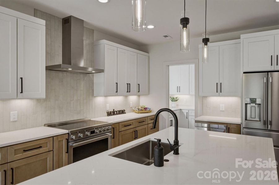 This gourmet kitchen features quartz countertops, syllish cabinetry, tiled backspash, and a Frigidaire professional appliance package that includes a 36" induction range with a stainless hood for kitchen exhaust. This gourmet kitchen features quartz countertops, syllish cabinetry, tiled backspash, and a Frigidaire professional appliance package that includes a 36" induction range with a stainless hood for kitchen exhaust.