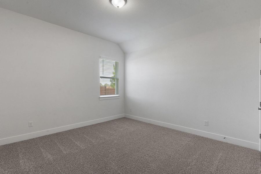 A well-lit bedroom features a window with blinds, creating a comfortable personal retreat.