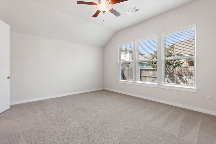 Additional living space with light colored carpet, vaulted ceiling, and a ceiling fan