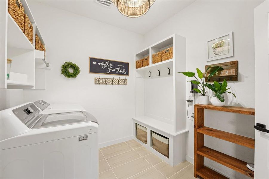 Mudroom with washing machine and dryer and light tile patterned floors