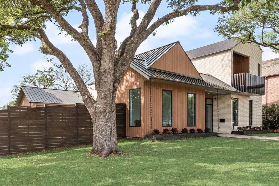 The front elevation blends modern design with warm, natural textures, a striking standing seam metal roof and a private balcony.