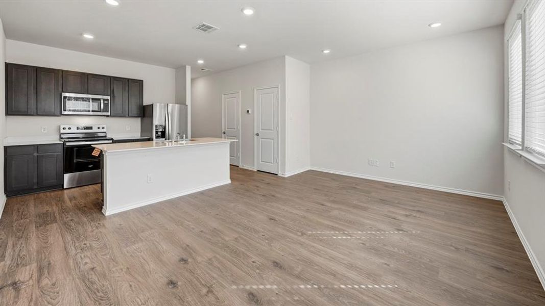Kitchen with appliances with stainless steel finishes, a kitchen island with sink, recessed lighting, light wood-style floors, and open floor plan