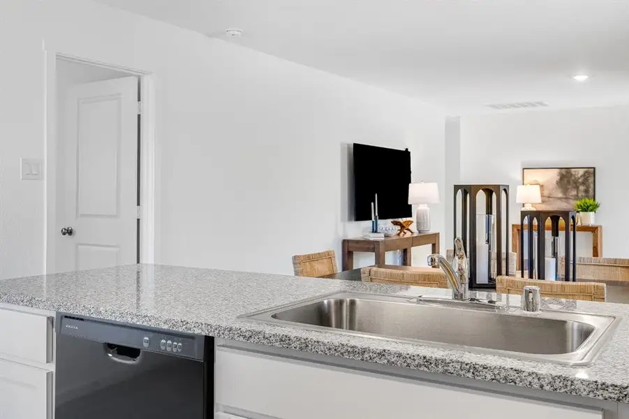 Kitchen featuring white cabinetry, dishwasher, and light stone countertops