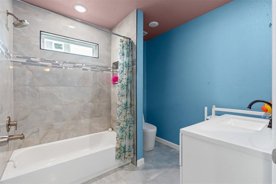 Bathroom featuring vanity, shower / bath combo with shower curtain, and light tile patterned floors Bathroom featuring vanity, shower / bath combo with shower curtain, and light tile patterned floors