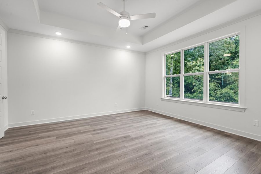 Spare room featuring a raised ceiling, recessed lighting, light wood finished floors, and a ceiling fan