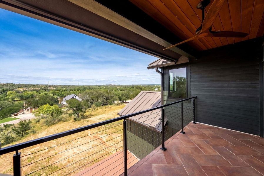 A covered balcony features tiled flooring and expansive views of the rolling countryside.