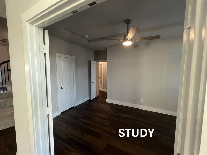 Room featuring dark wood-finish flooring, light-toned walls, and a tray ceiling Room featuring dark wood-finish flooring, light-toned walls, and a tray ceiling