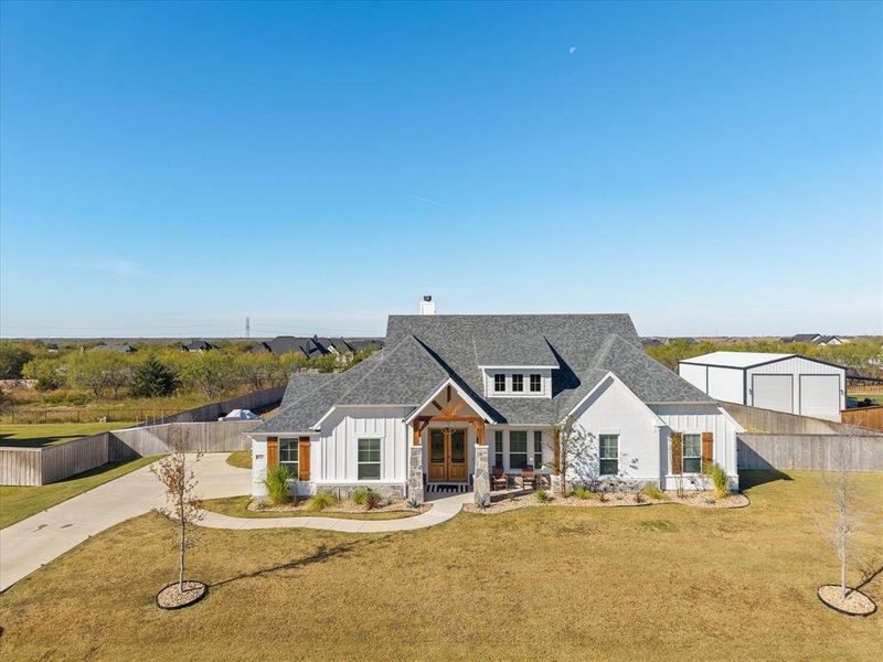 Modern farmhouse style home with stone siding, board and batten siding, a chimney, and a shingled roof