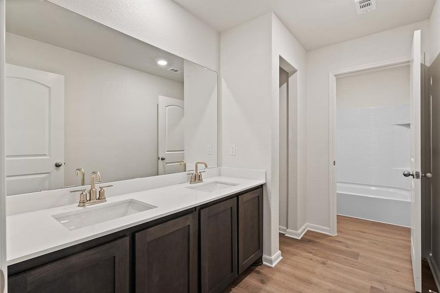Full bathroom featuring double vanity, wood finished floors, and a tub