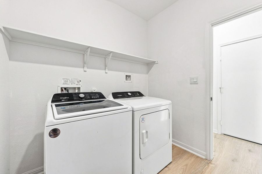 Functional design highlights this utility space equipped with overhead shelving and durable wood-look flooring.