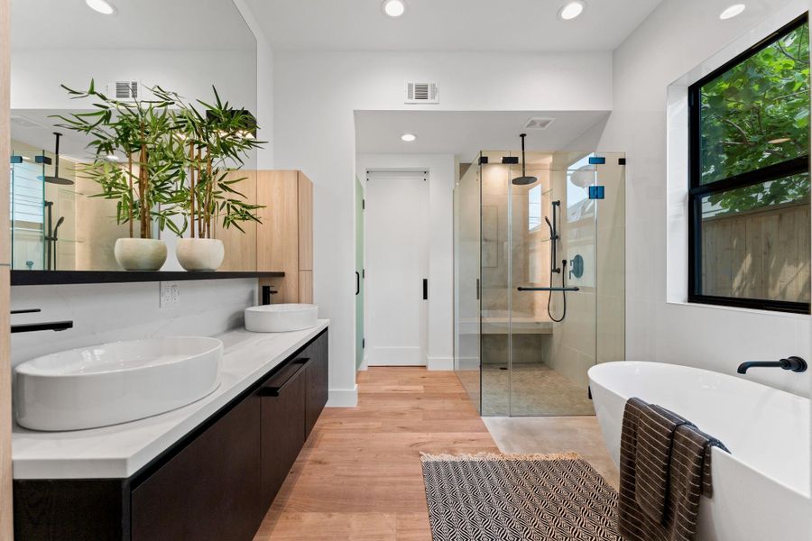 Frameless glass shower with dual rainfall heads, floating cabinetry, and seamless tilework create everyday serenity.