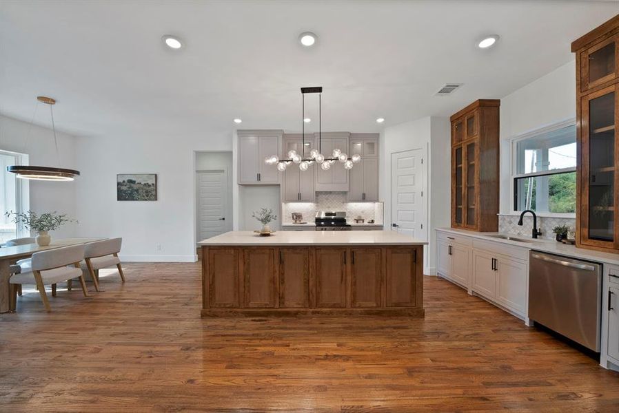 Kitchen with healthy amount of natural light, brown cabinetry, glass insert cabinets, hanging light fixtures, and recessed lighting Kitchen with healthy amount of natural light, brown cabinetry, glass insert cabinets, hanging light fixtures, and recessed lighting