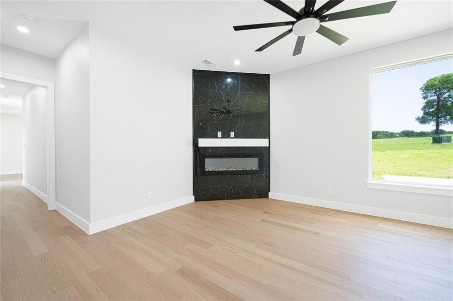 Unfurnished room featuring a fireplace, light wood finished floors, recessed lighting, and a ceiling fan
