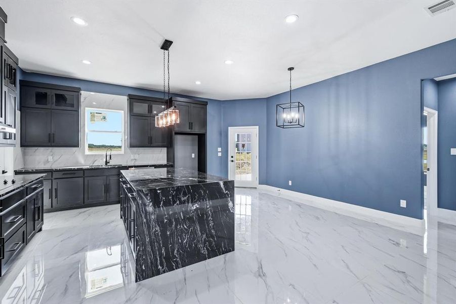 Kitchen with a kitchen island, light marble finish floors, pendant lighting, tasteful backsplash, and recessed lighting