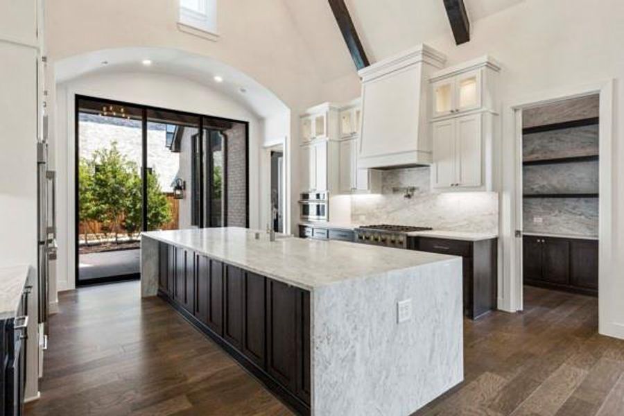 Kitchen with glass insert cabinets, white cabinets, light stone counters, dark wood-type flooring, and high vaulted ceiling Kitchen with glass insert cabinets, white cabinets, light stone counters, dark wood-type flooring, and high vaulted ceiling