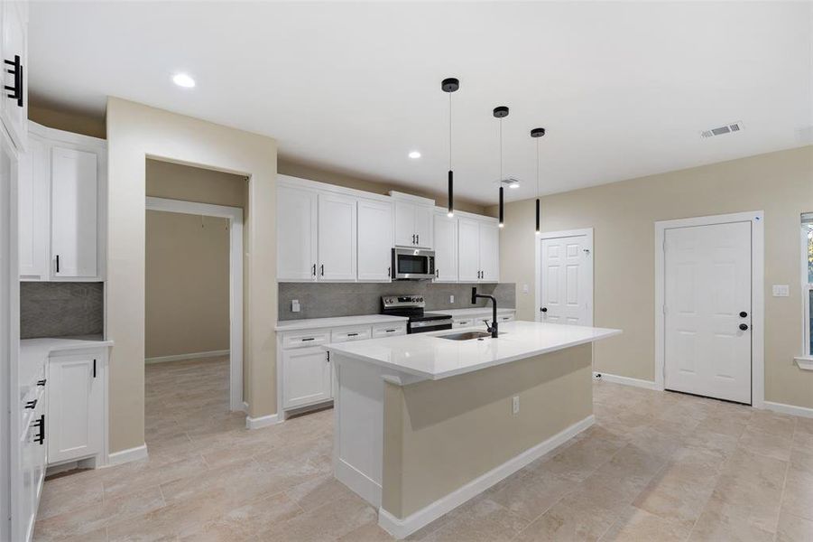 Kitchen featuring stainless steel appliances, tasteful backsplash, pendant lighting, a kitchen island with sink, and white cabinets