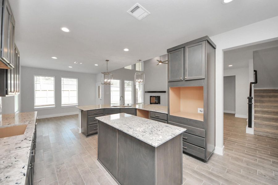 This generously spacious kitchen is a dream realized! With a massive granite island, high ceilings, soft close cabinets, granite countertops, stainless steel appliances, a sleek tile backsplash, recessed lighting, and an extended counter area, it offers both style and practicality. All this opens up to the expansive family room, creating a perfect hub for gatherings.