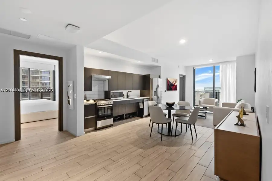 Open-concept interior featuring wood-finish tile flooring, custom flat-panel cabinetry, stainless steel kitchen appliances, and floor-to-ceiling windows Open-concept interior featuring wood-finish tile flooring, custom flat-panel cabinetry, stainless steel kitchen appliances, and floor-to-ceiling windows