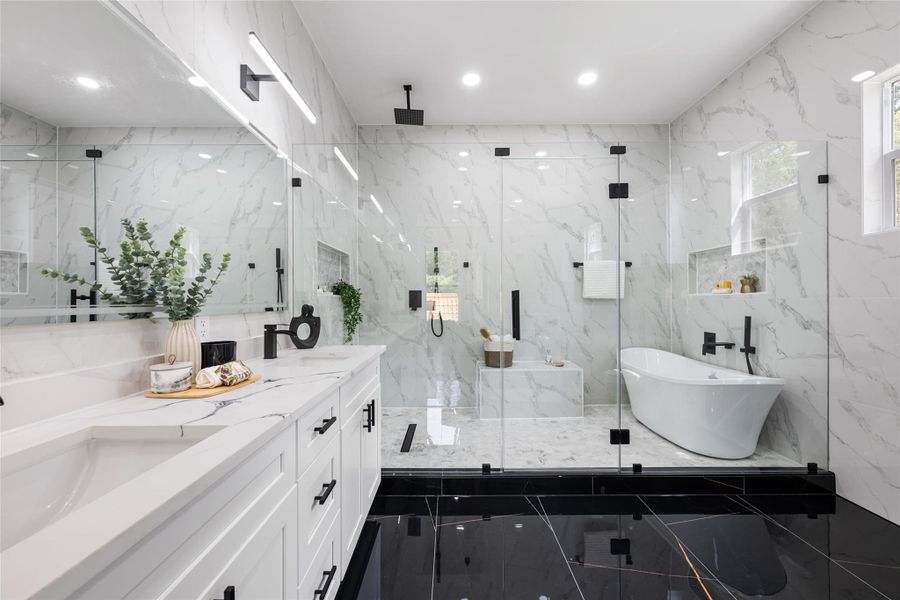 Modern bathroom featuring a freestanding tub, glass-enclosed shower with bench, dual vanity with undermount sinks, and black-finish hardware