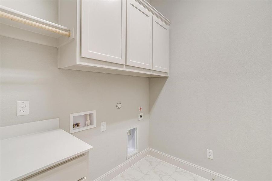 Laundry area featuring light tile patterned flooring, gas dryer hookup, washer hookup, cabinets, and electric dryer hookup