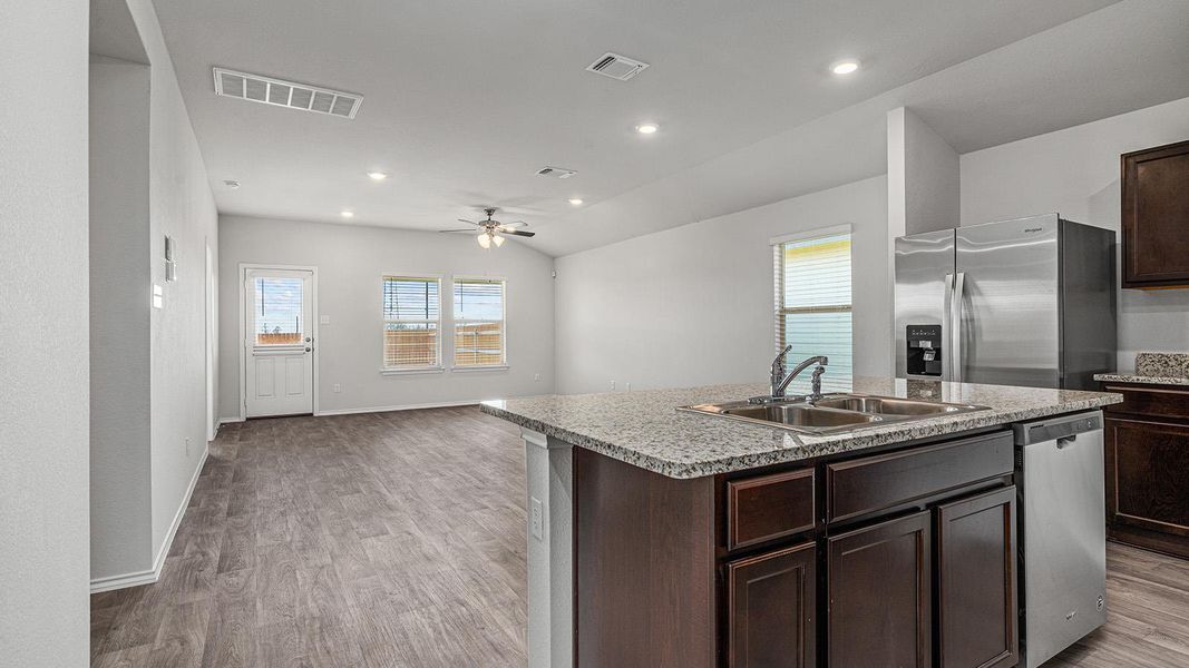 Kitchen with dark wood finish cabinets, stainless steel appliances, open floor plan, an island with sink, and ceiling fan Kitchen with dark wood finish cabinets, stainless steel appliances, open floor plan, an island with sink, and ceiling fan