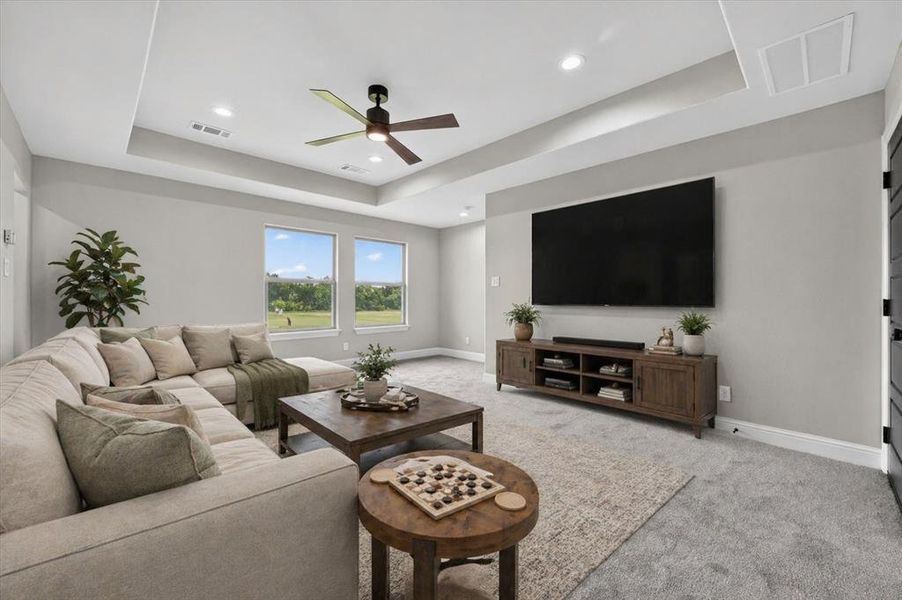 Spacious living area featuring a tray ceiling with recessed lighting and a ceiling fan, dual windows, and light gray wall finishes