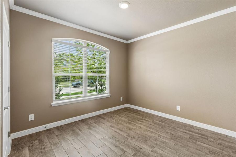 Room featuring a large arched window with horizontal blinds, wood-finish flooring, recessed lighting, and crown molding