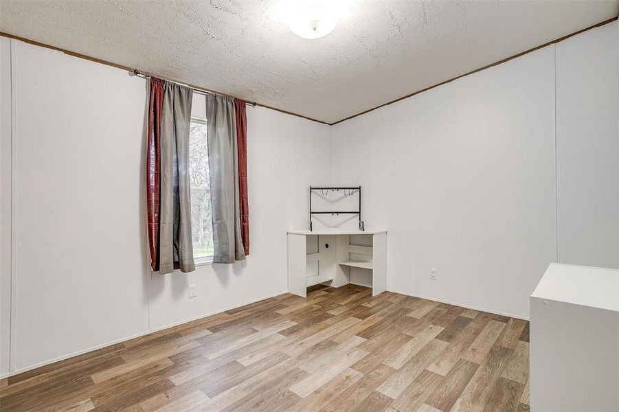 Empty room with a textured ceiling and light wood-type flooring