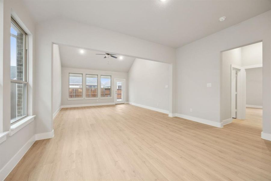 Spare room featuring lofted ceiling, light hardwood / wood-style flooring, and ceiling fan