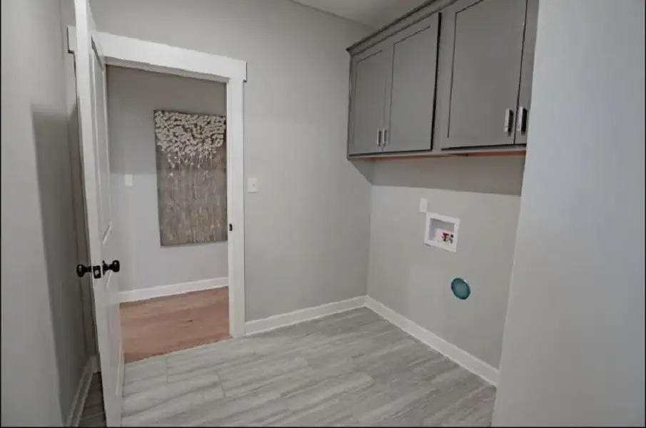 Laundry area featuring tile flooring, painted cabinetry, and utility connections