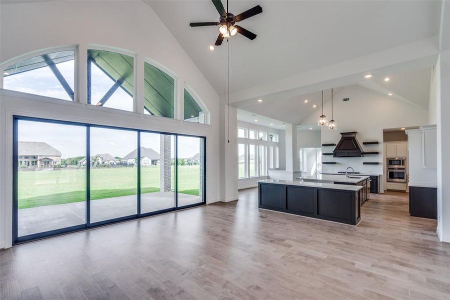 Kitchen with decorative light fixtures, high vaulted ceiling, a kitchen island with sink, and a wealth of natural light