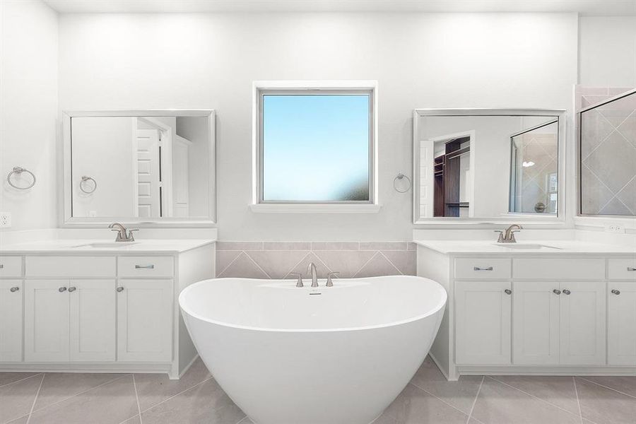 Primary bathroom with a soaking tub, ceramic tile patterned flooring, separate vanities, and a walk-in shower.