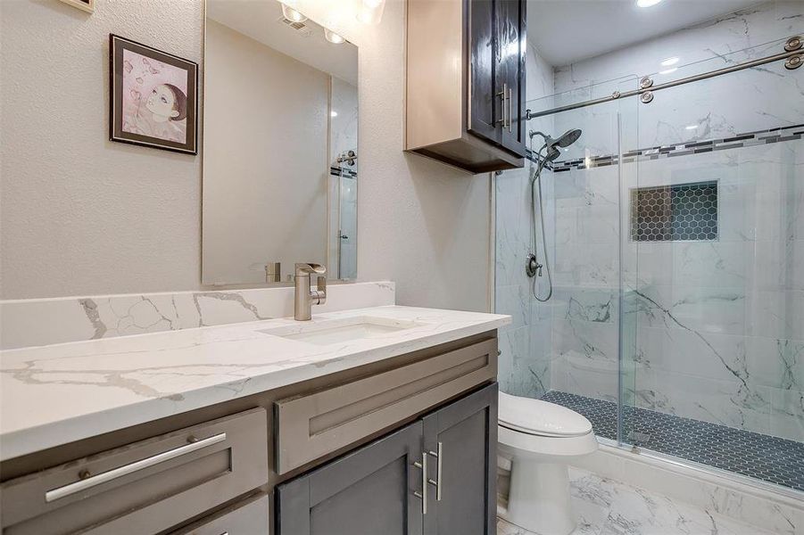 Bathroom with toilet, vanity, and walk in shower