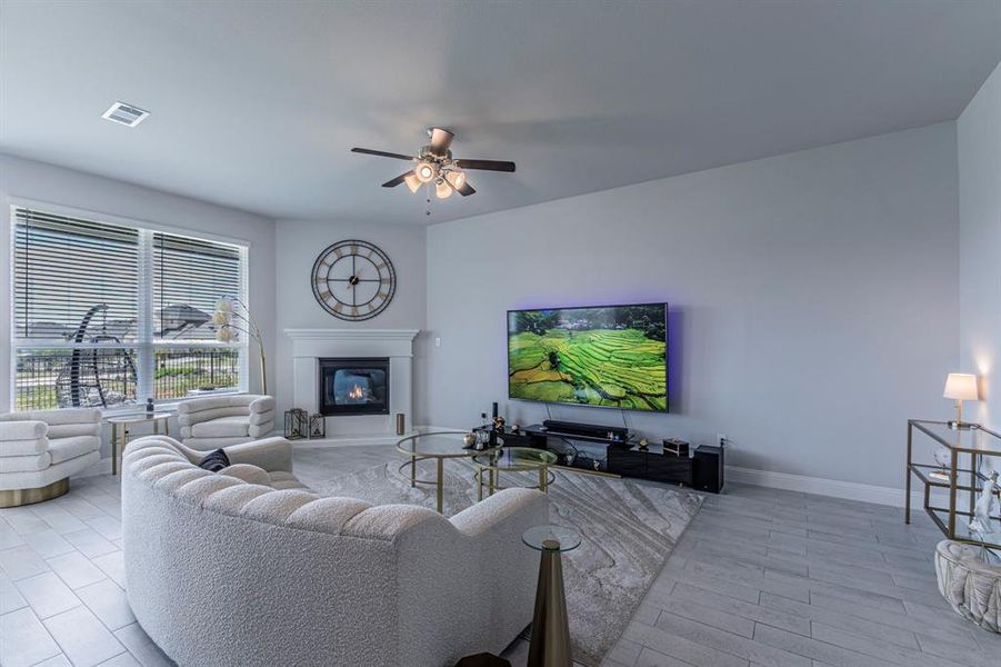 Living area with a ceiling fan, a glass covered fireplace, and light wood-style floors Living area with a ceiling fan, a glass covered fireplace, and light wood-style floors