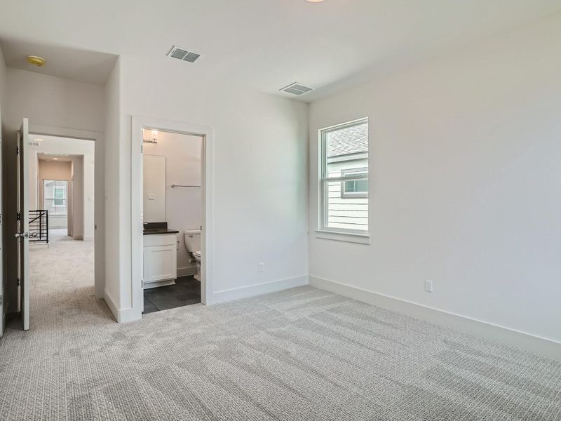 Unfurnished bedroom featuring light carpet and connected bathroom