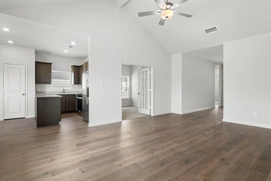 Unfurnished living room with high vaulted ceiling, dark wood finished floors, beam ceiling, recessed lighting, and ceiling fan Unfurnished living room with high vaulted ceiling, dark wood finished floors, beam ceiling, recessed lighting, and ceiling fan