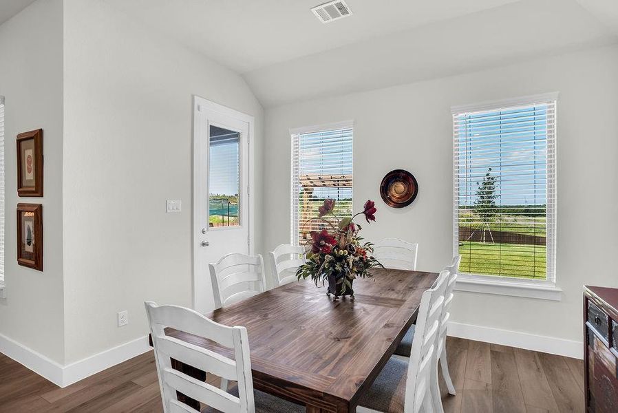 Dining/Breakfast room featuring wood-finish flooring, white walls, and backyard views opens to Kitchen and Living rooms