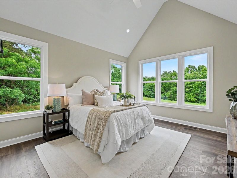 Spacious primary suite features soaring vaulted ceilings, abundant natural light, and peaceful views of the private backyard.