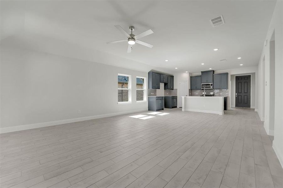 Unfurnished living room featuring ceiling fan, recessed lighting, visible vents, baseboards, and light wood-type flooring Unfurnished living room featuring ceiling fan, recessed lighting, visible vents, baseboards, and light wood-type flooring