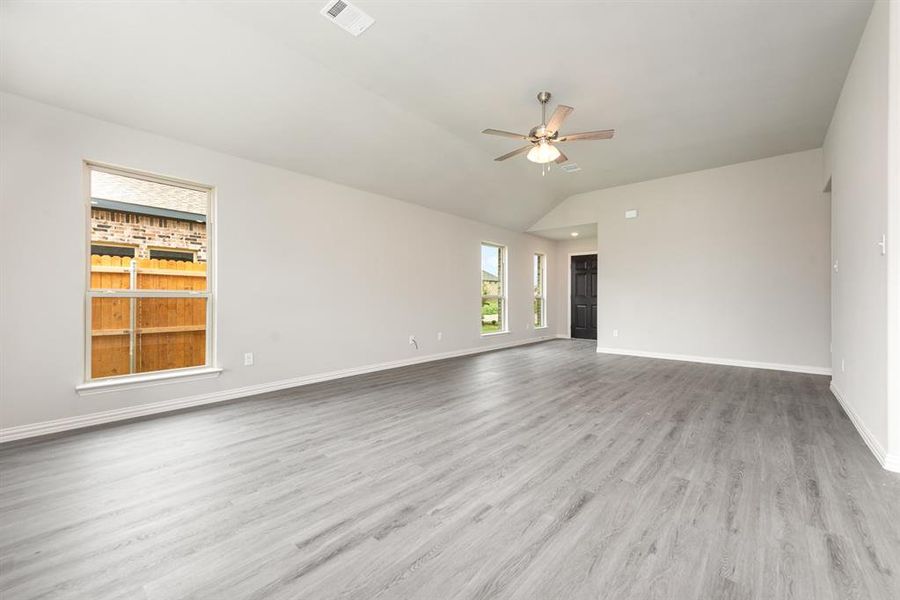 Unfurnished living room featuring light wood-type flooring, ceiling fan, and vaulted ceiling