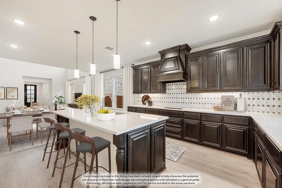 Kitchen with dark wood cabinets, large island with seating, and patterned tile backsplash open to dining area