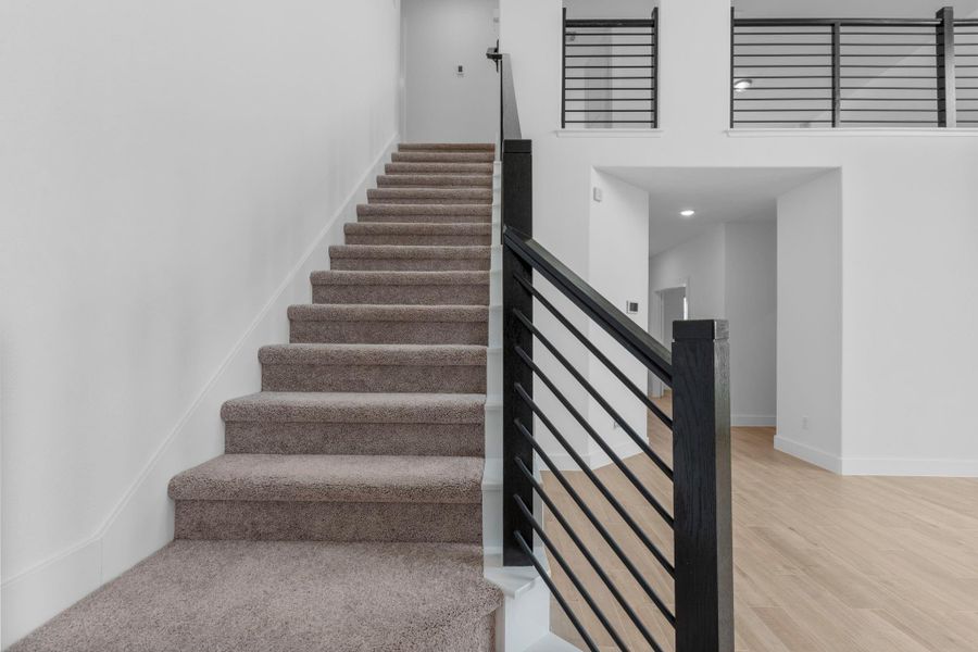 Carpeted staircase accented with a striking modern cable iron railing, creating an elegant transition to the second floor. **Image Representative of Plan Only and May Vary as Built**.