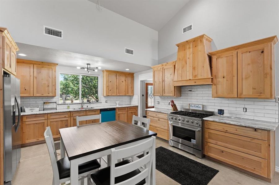 Eat-in-kitchen with sealed concrete, knotty alder wood cabinets, backsplash, 6 burner commercial grade gas stove and oven, plumbed for a pot filler and refrigerator.